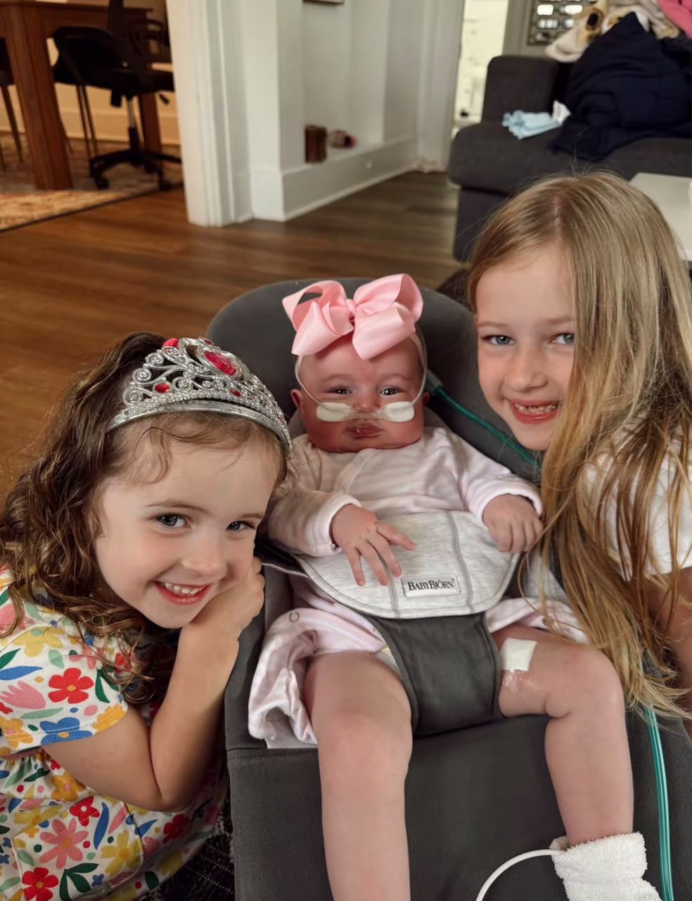 Alice smiling between her two big sisters at home